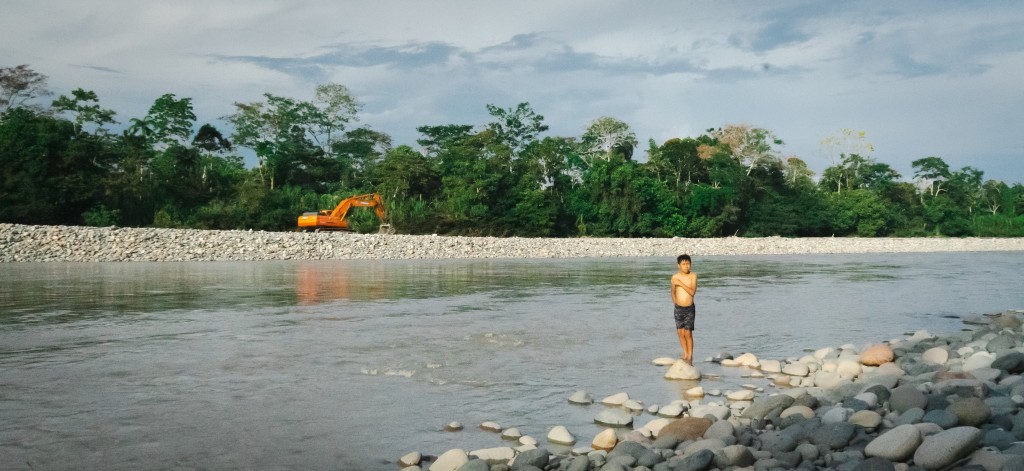 Young boy standing on top of a rock in an amazon river